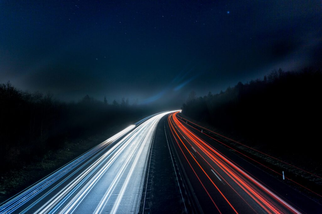 pexels-photo-315938-315938 Long exposure night shot capturing stunning red and white light trails on a highway under a starry sky.
